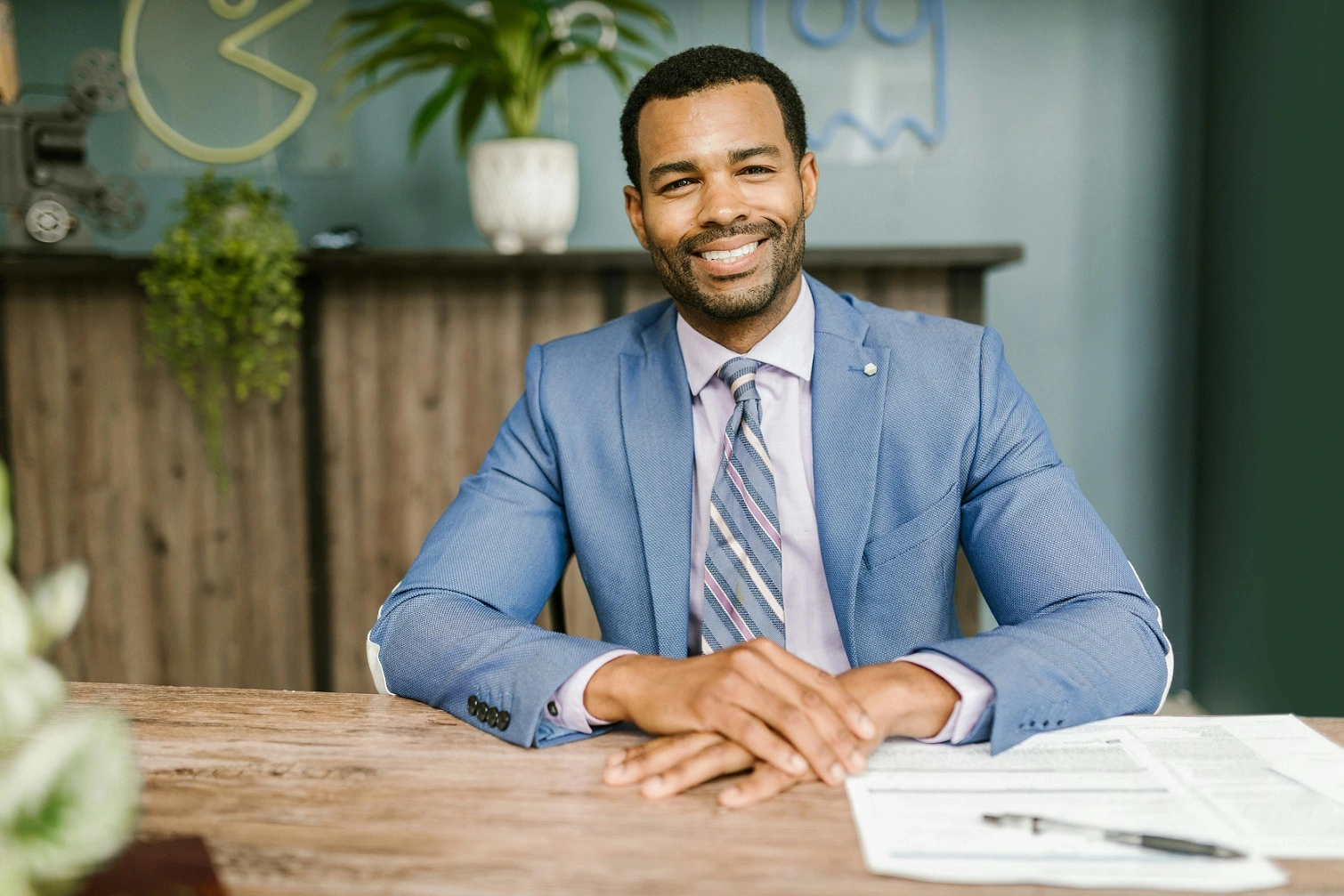 Foto de um homem sentando em uma mesa e sorrindo, ilustrando o conceito de Treinamento em Corretoras de Seguros
